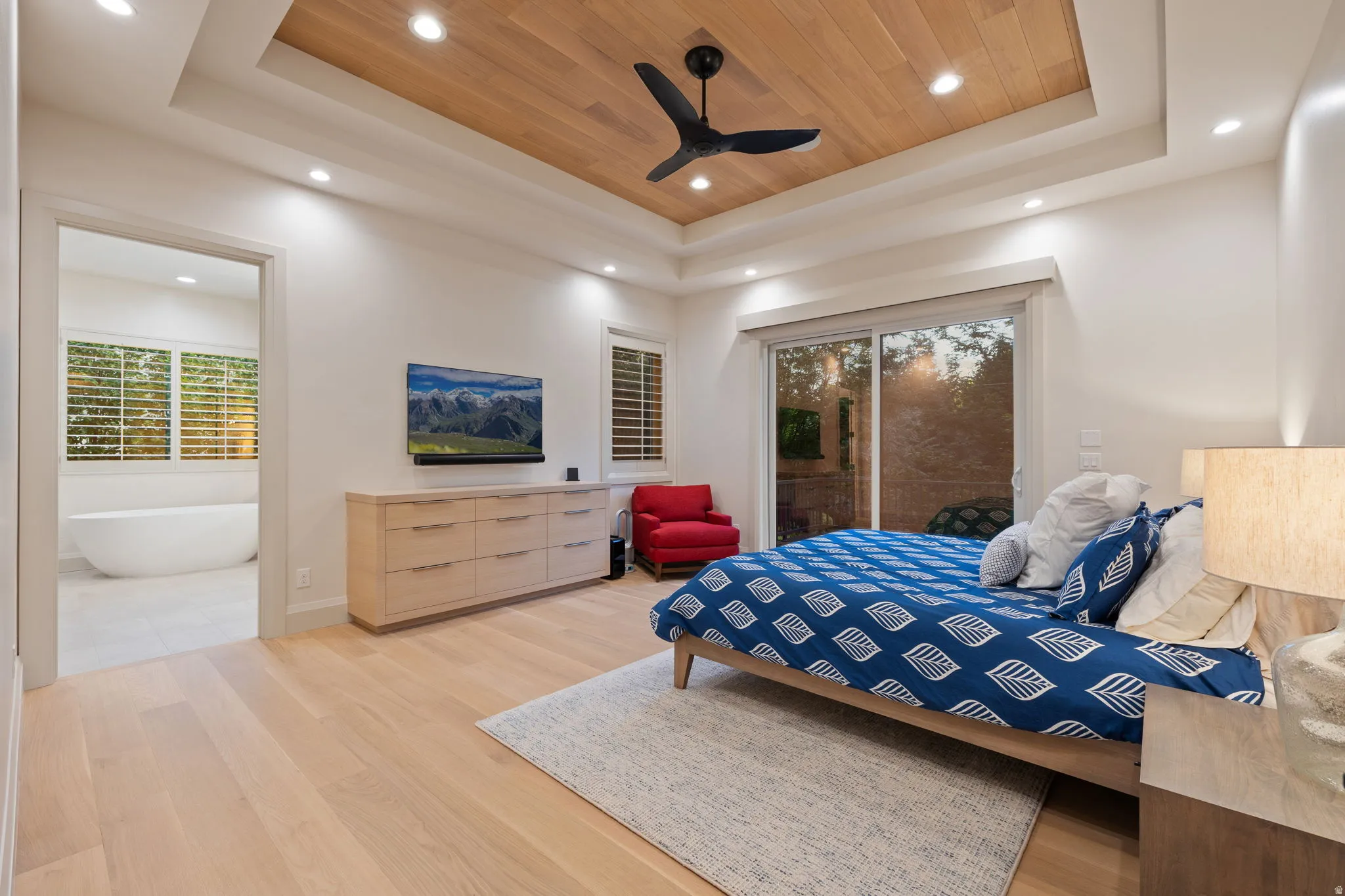 Recessed ceiling with wood-finish inlay and ceiling fan, light wood-finish flooring, and sliding glass door
