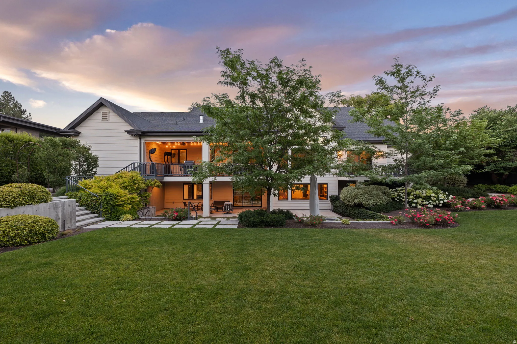 Expansive rear yard featuring a manicured lawn, lush landscaping, and mature trees
