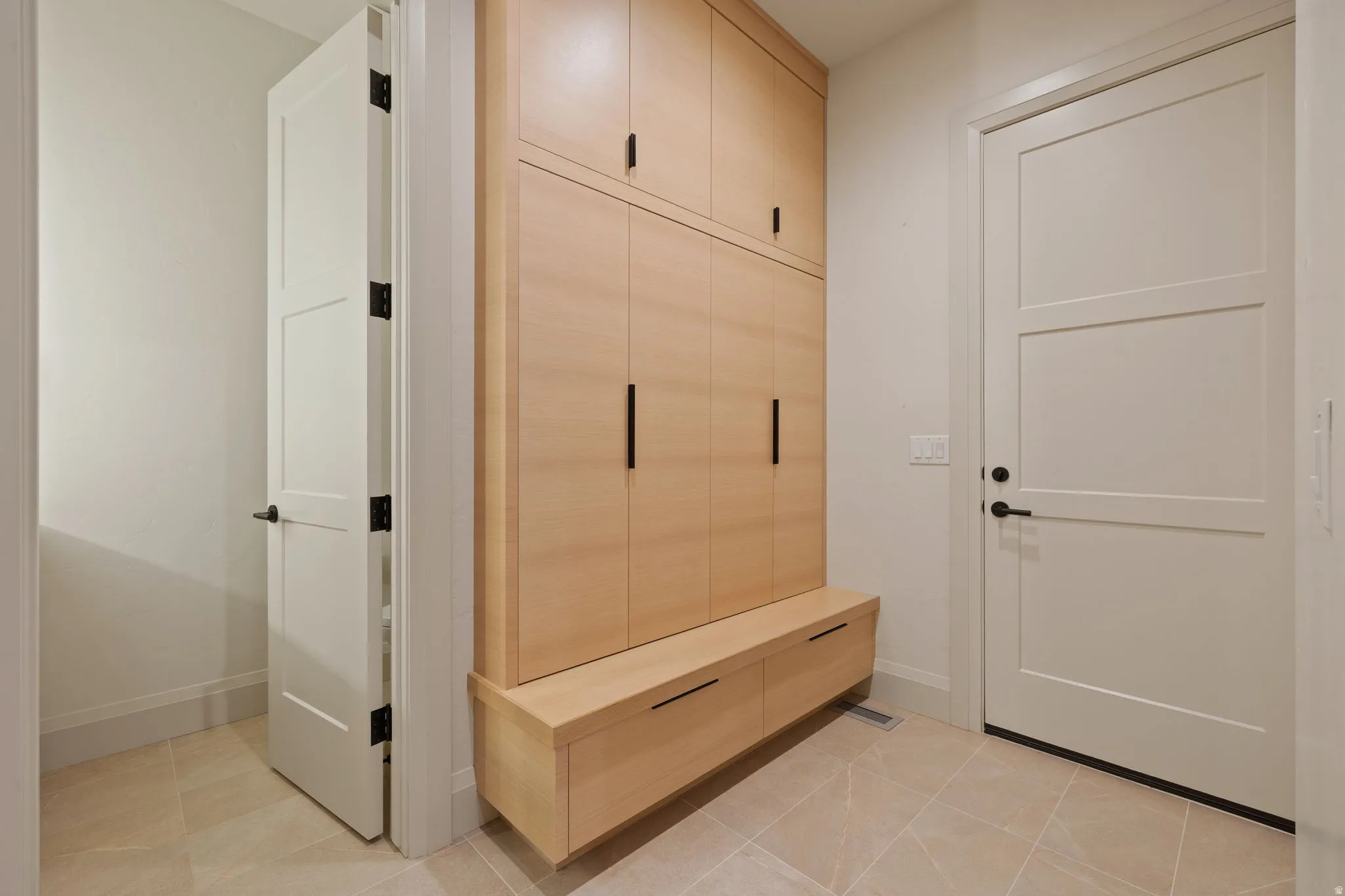Built-in wood-finish cabinetry featuring black hardware, integrated bench seating, and storage drawers