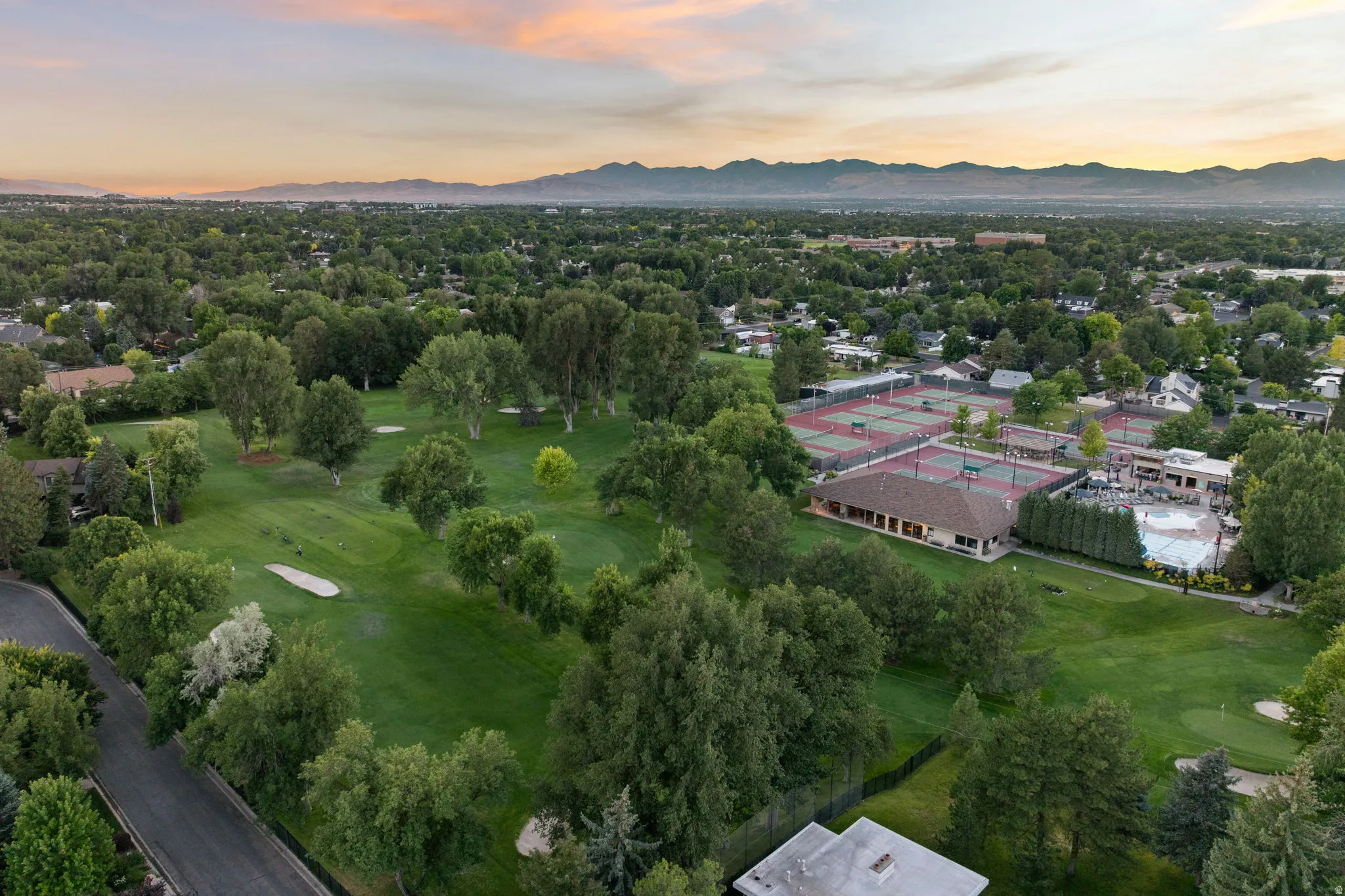 Expansive golf course and tennis club grounds featuring multiple tennis courts, a large swimming pool, and a clubhouse building