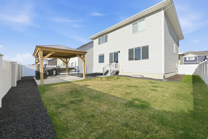 Backyard featuring a wooden gazebo with a metal roof over a concrete patio, a manicured lawn, and a white privacy fence