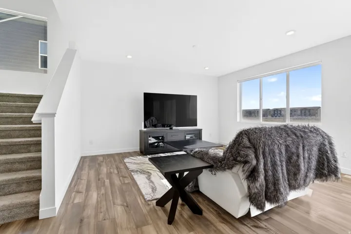 Spacious living area featuring plank wood-finish flooring, recessed lighting, and a large multi-pane window