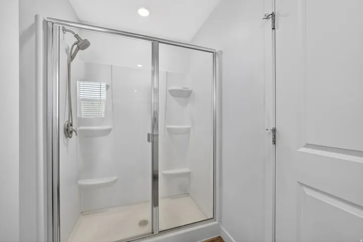 Walk-in shower with clear glass enclosure and brushed nickel fixtures