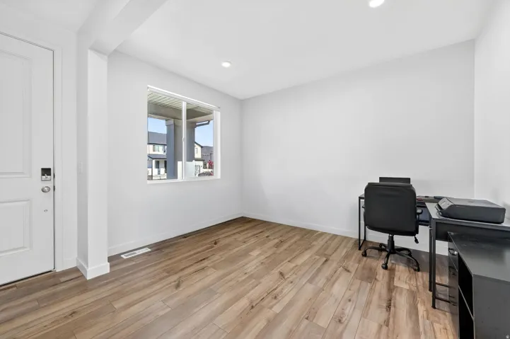 Entryway featuring wood-finish flooring, recessed lighting, and a white paneled door with contemporary hardware