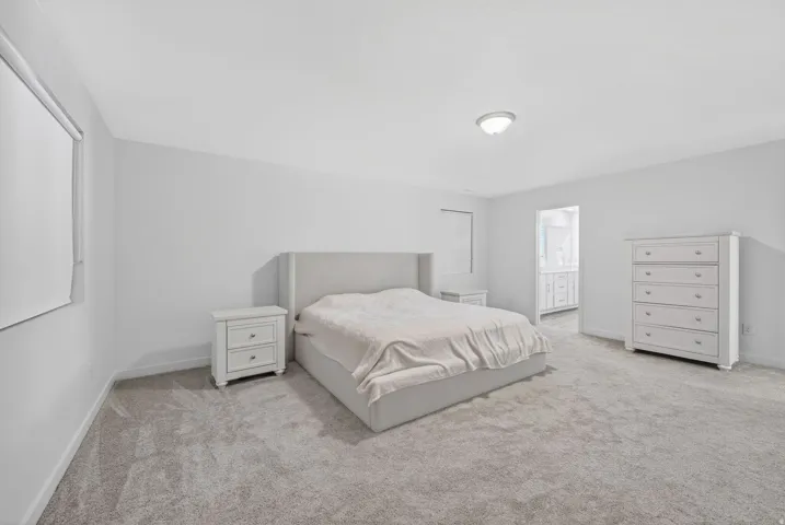 Spacious room featuring light gray carpeting, recessed lighting, and a window with roller shade
