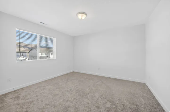 Room featuring neutral wall finishes, light-colored carpet, and a window with horizontal blinds