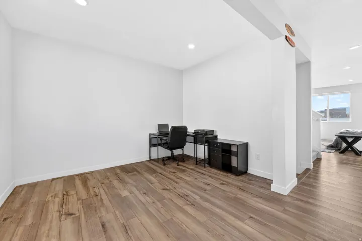 Spacious room featuring wood-finish flooring, recessed lighting, and white baseboards