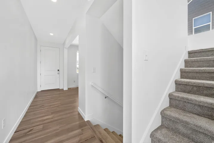 Entryway featuring wood-finish flooring, a white paneled door, recessed lighting, and a staircase with carpeted treads
