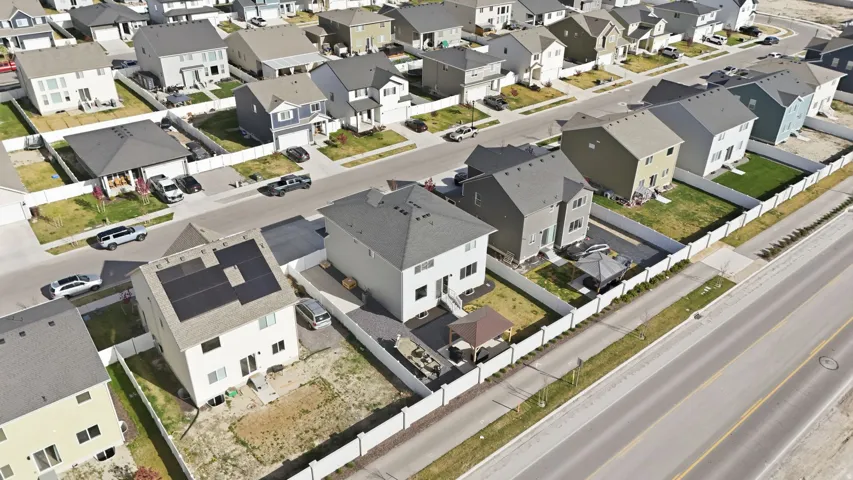 Residential property featuring a light-colored exterior and a dark shingle roof with visible solar panels