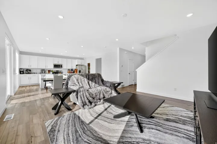 Open-concept living space featuring wood-finish flooring, recessed lighting, and white walls