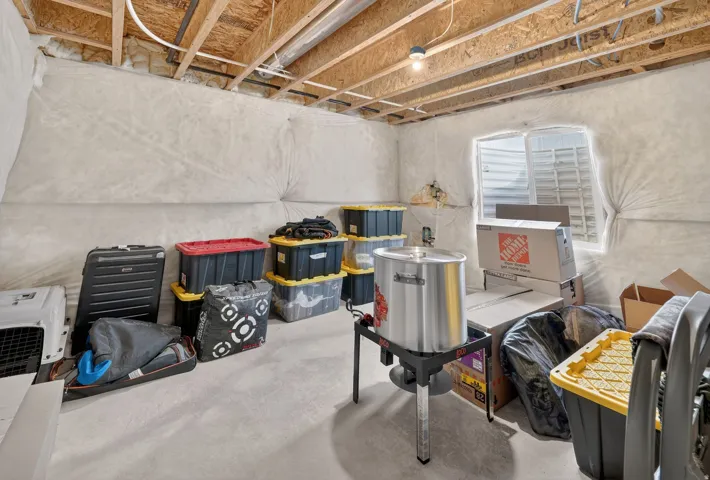 Unfinished basement space featuring exposed wood joists, concrete flooring, and a visible window opening