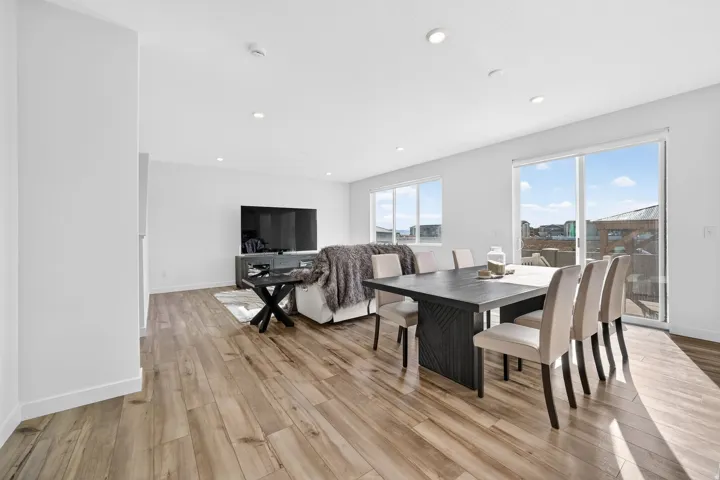 Open concept living and dining area featuring wood-finish flooring, recessed lighting, and large windows with abundant natural light