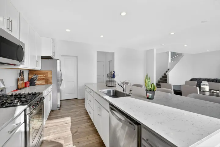 Modern kitchen featuring white cabinetry, light-toned wood-finish flooring, and white countertops