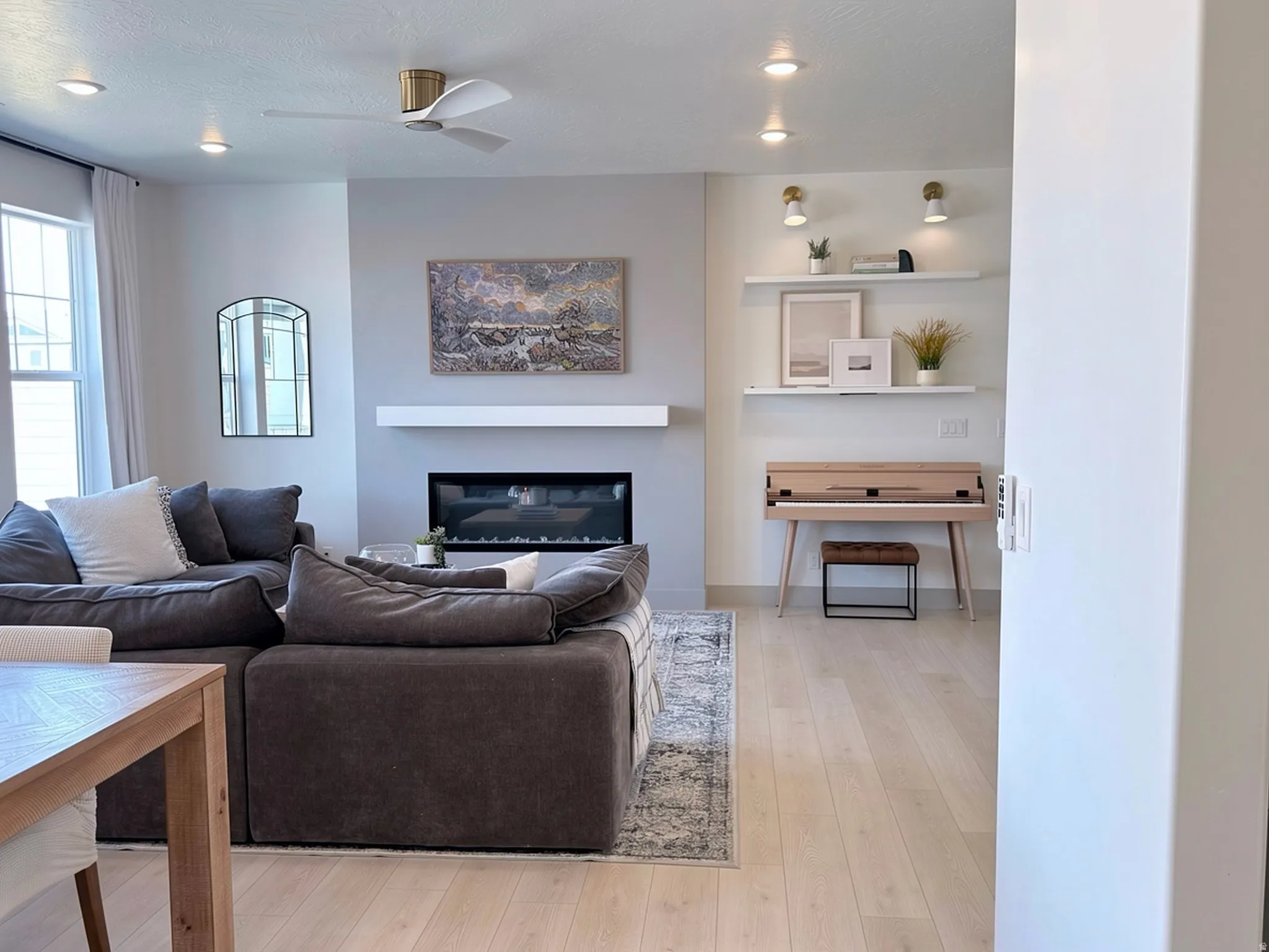 Spacious living area featuring a built-in electric fireplace with a white mantel, light wood-finish flooring, recessed lighting, and a modern ceiling fan