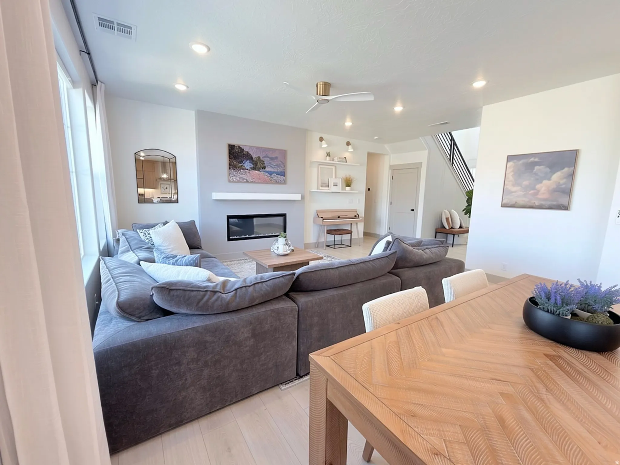 Open-concept living space featuring wood-finish flooring, a contemporary fireplace with a mantel, recessed lighting, and a ceiling fan