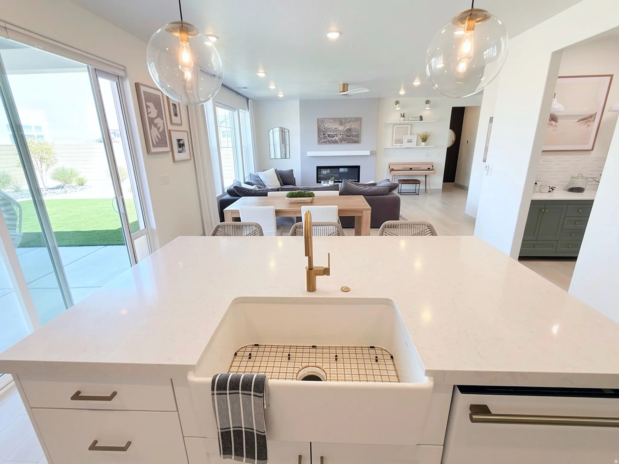 Spacious kitchen island featuring a farmhouse-style sink with a gold-tone faucet, white countertops, and integrated cabinetry