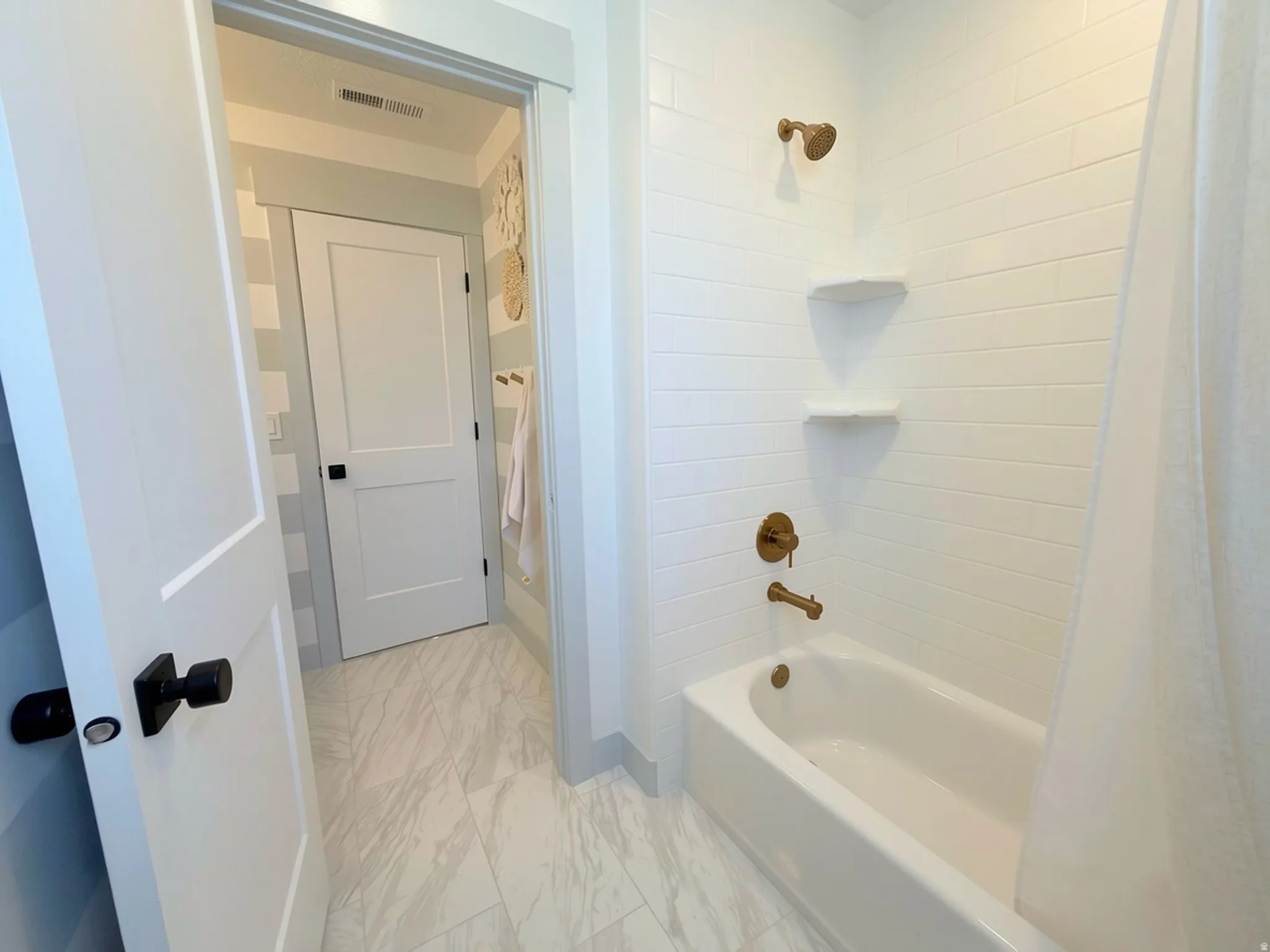 Bathtub with white subway tile surround and bronze-finish fixtures