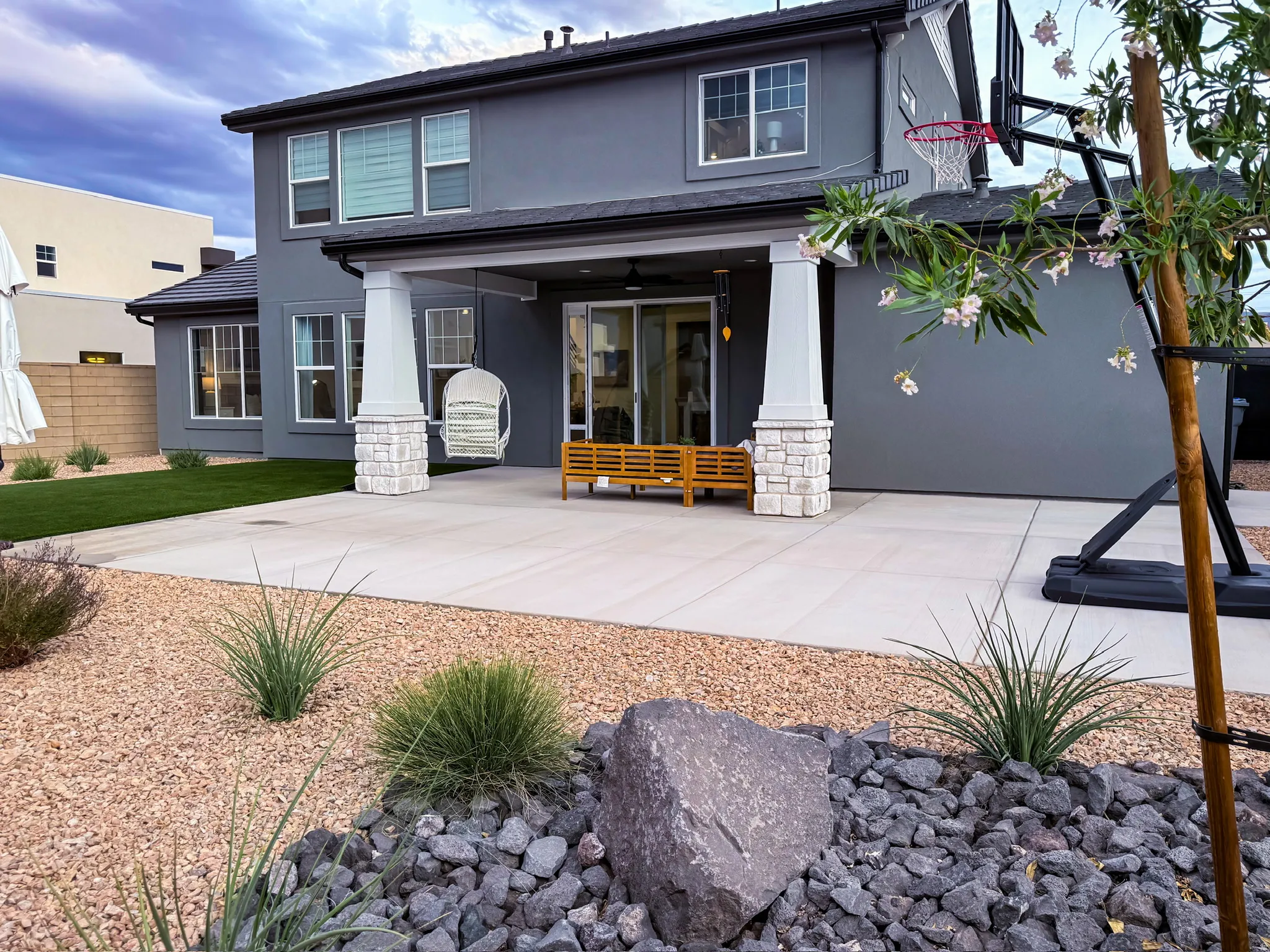 Expansive concrete patio with stone-wrapped columns and a covered outdoor living area