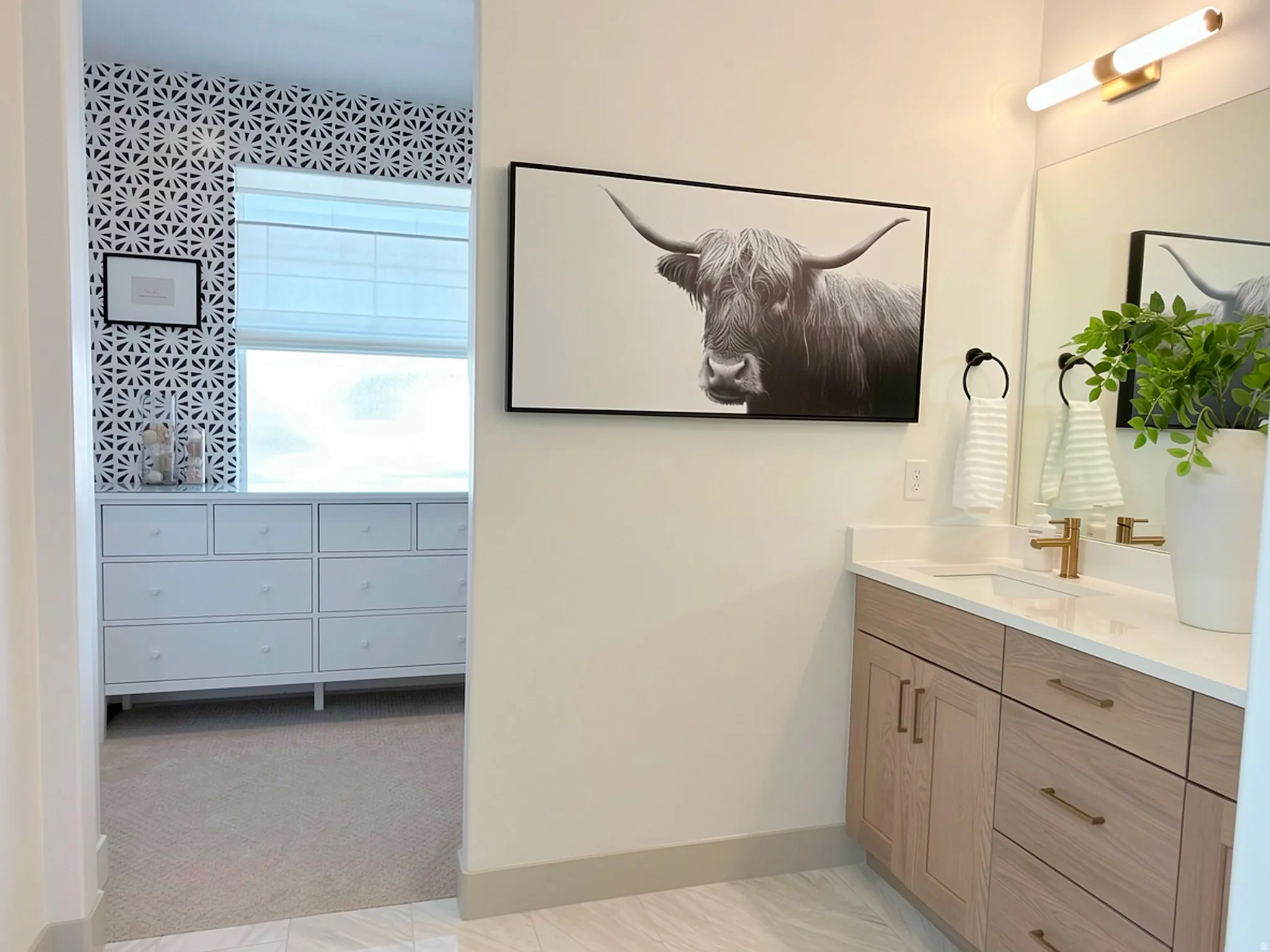 Modern bathroom vanity featuring light wood-finish cabinetry, a white countertop, and gold-tone fixtures