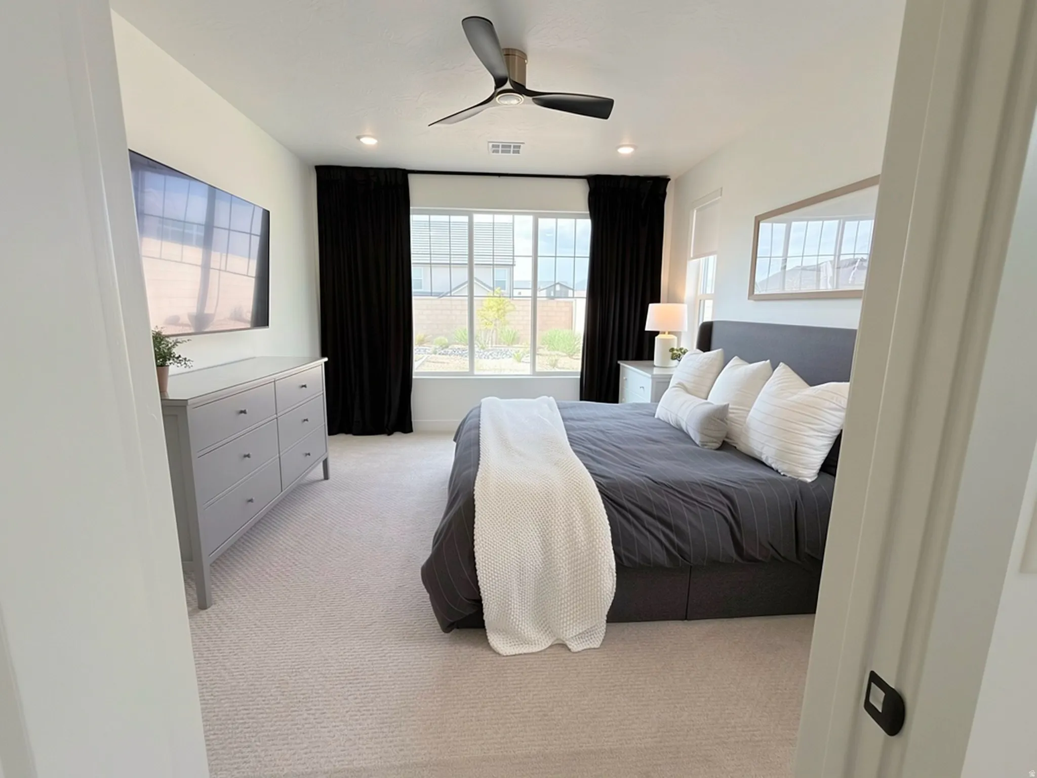 Carpeted room featuring a ceiling fan, recessed lighting, and a large window with white framing