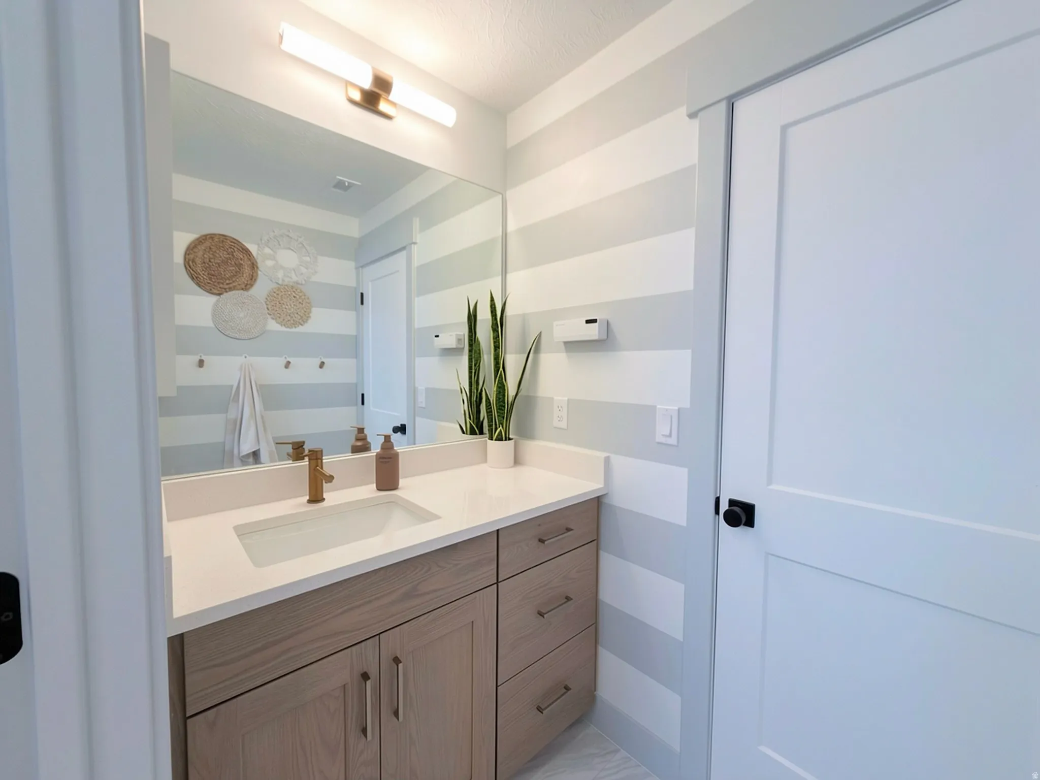 Bathroom featuring a light wood-finish vanity with a white countertop and rectangular undermount sink