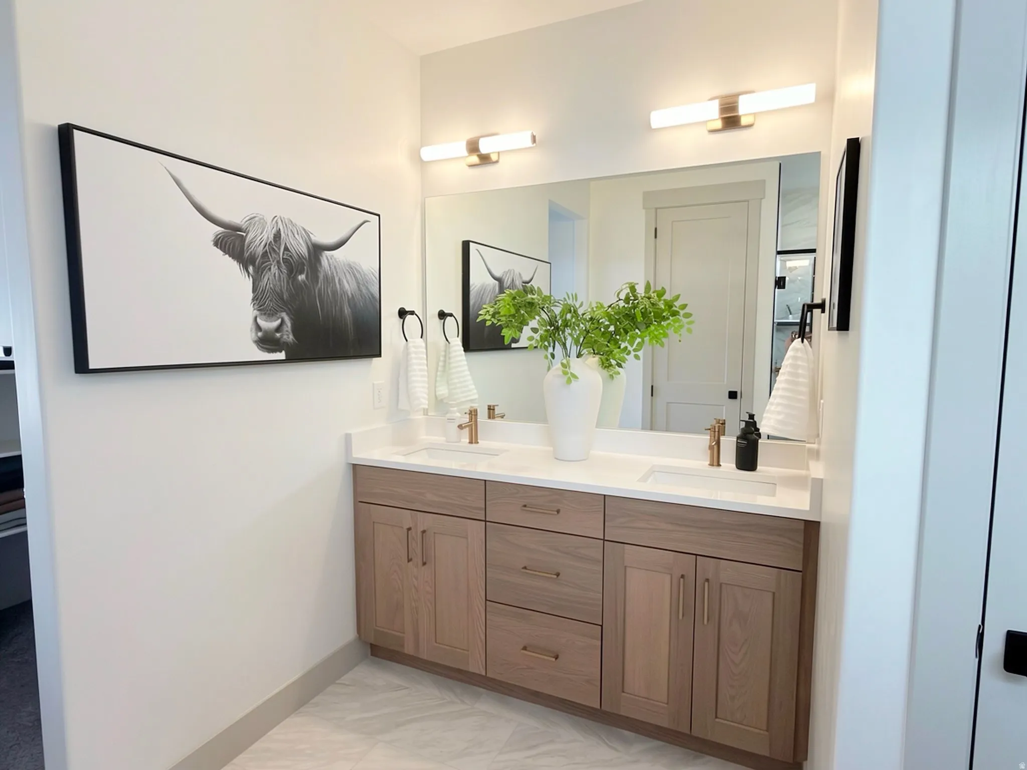 Dual vanity featuring wood-finish cabinetry, white countertops, and integrated rectangular sinks