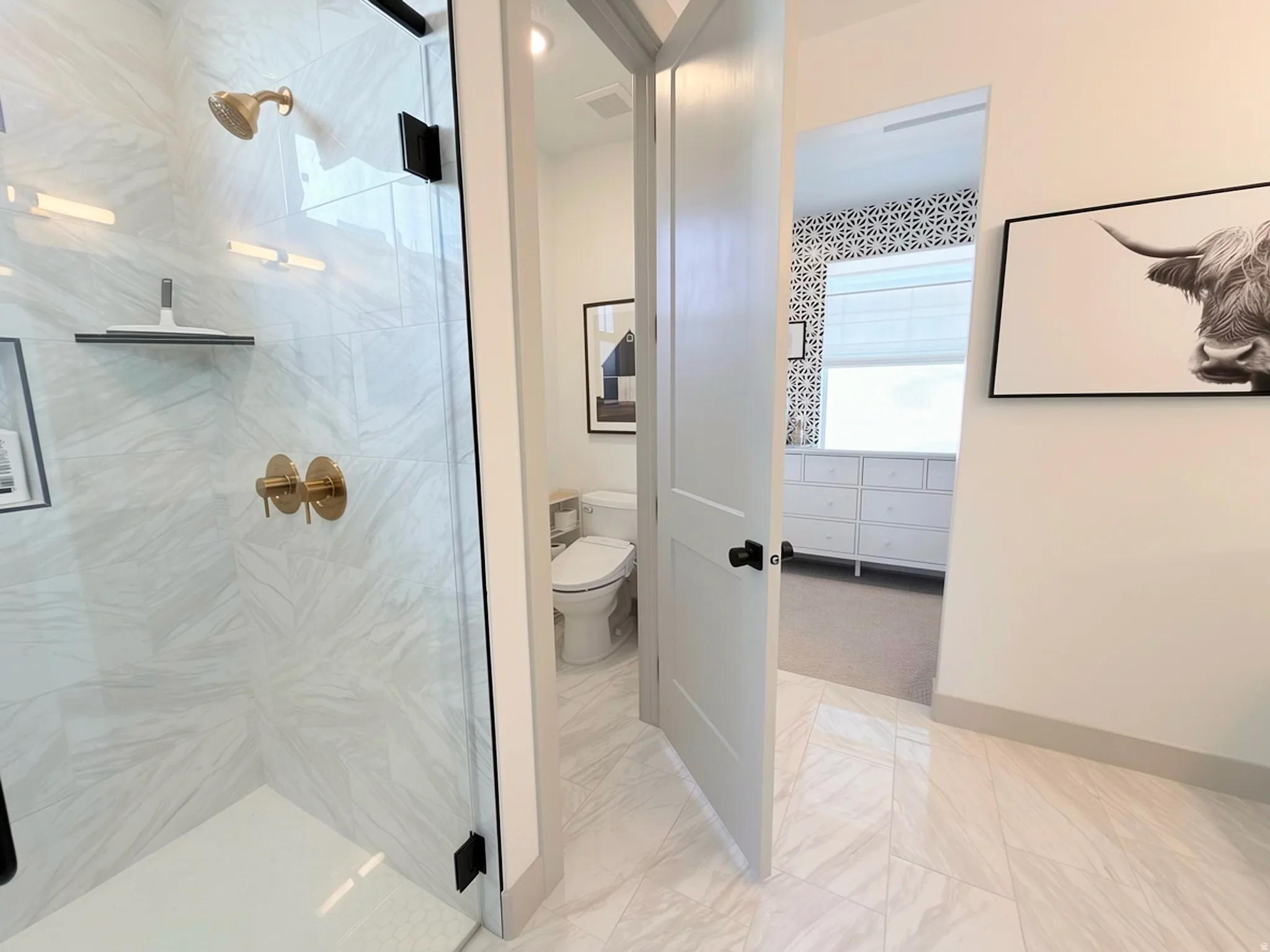 Spacious shower enclosure with a glass panel, gold-tone fixtures, and large-format tile surrounds