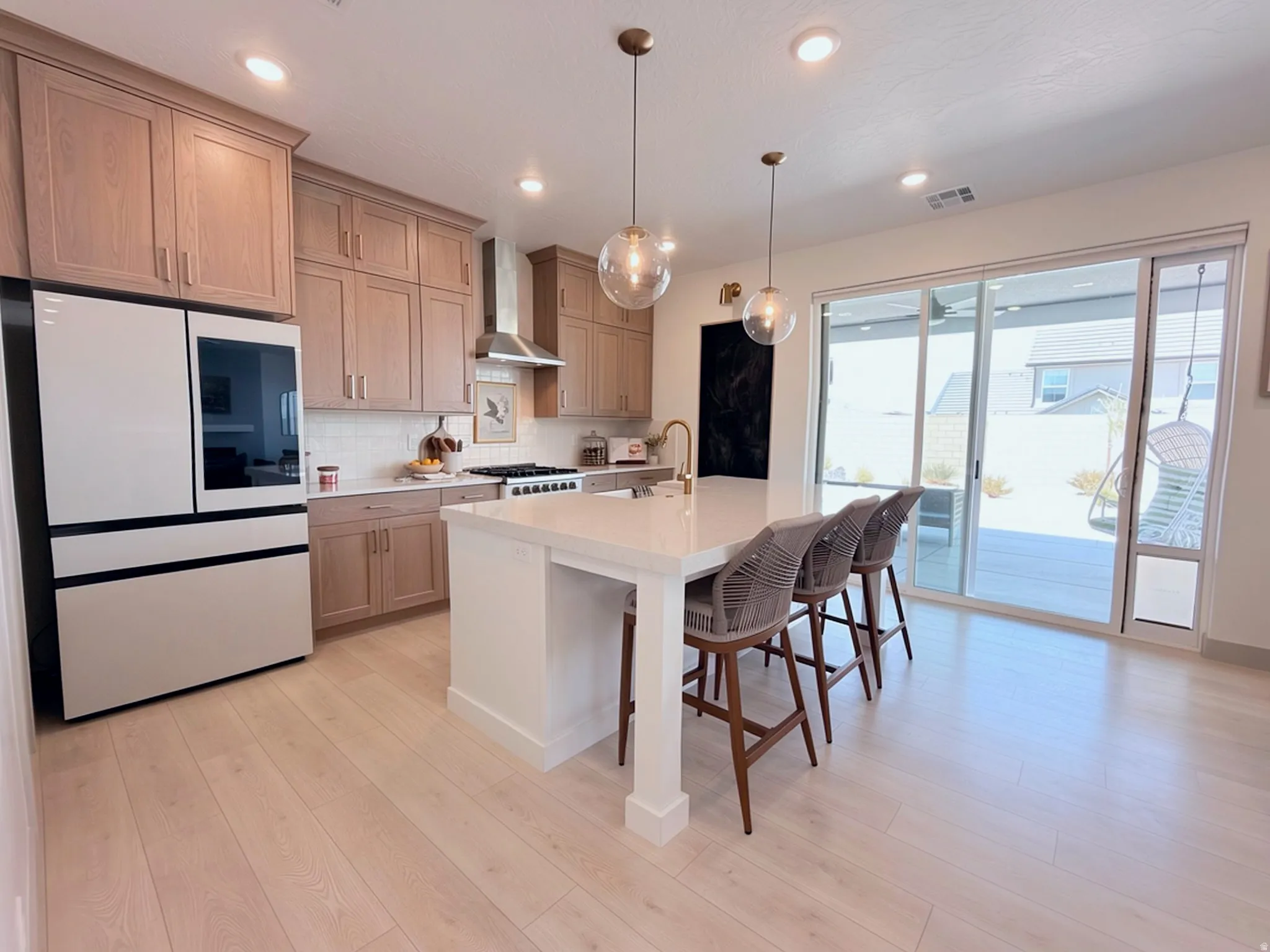 Spacious kitchen with wood-finish flooring, light-toned cabinetry, and an expansive center island with seating