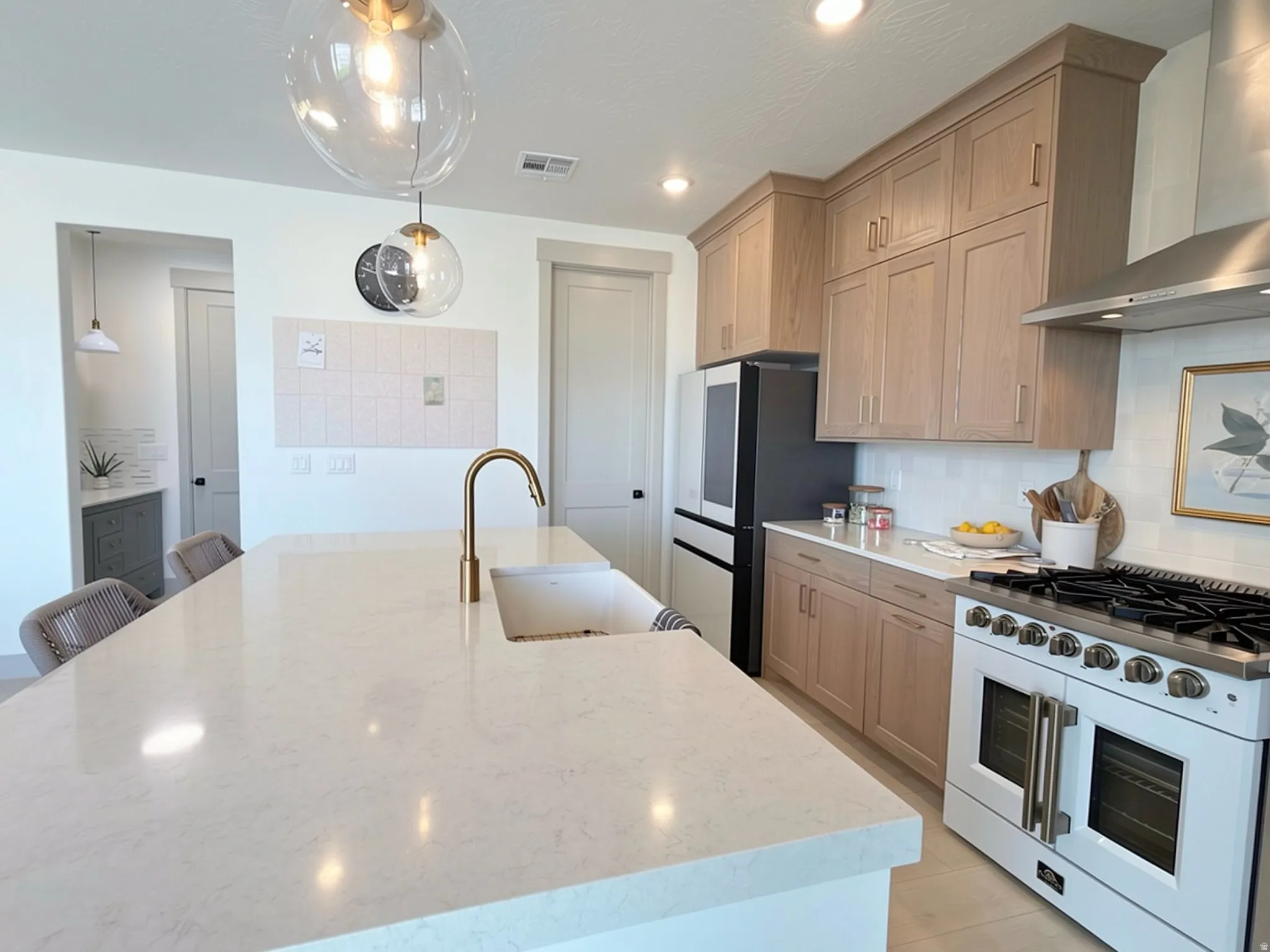 Spacious kitchen island featuring a white countertop and an integrated sink with a gold-tone faucet