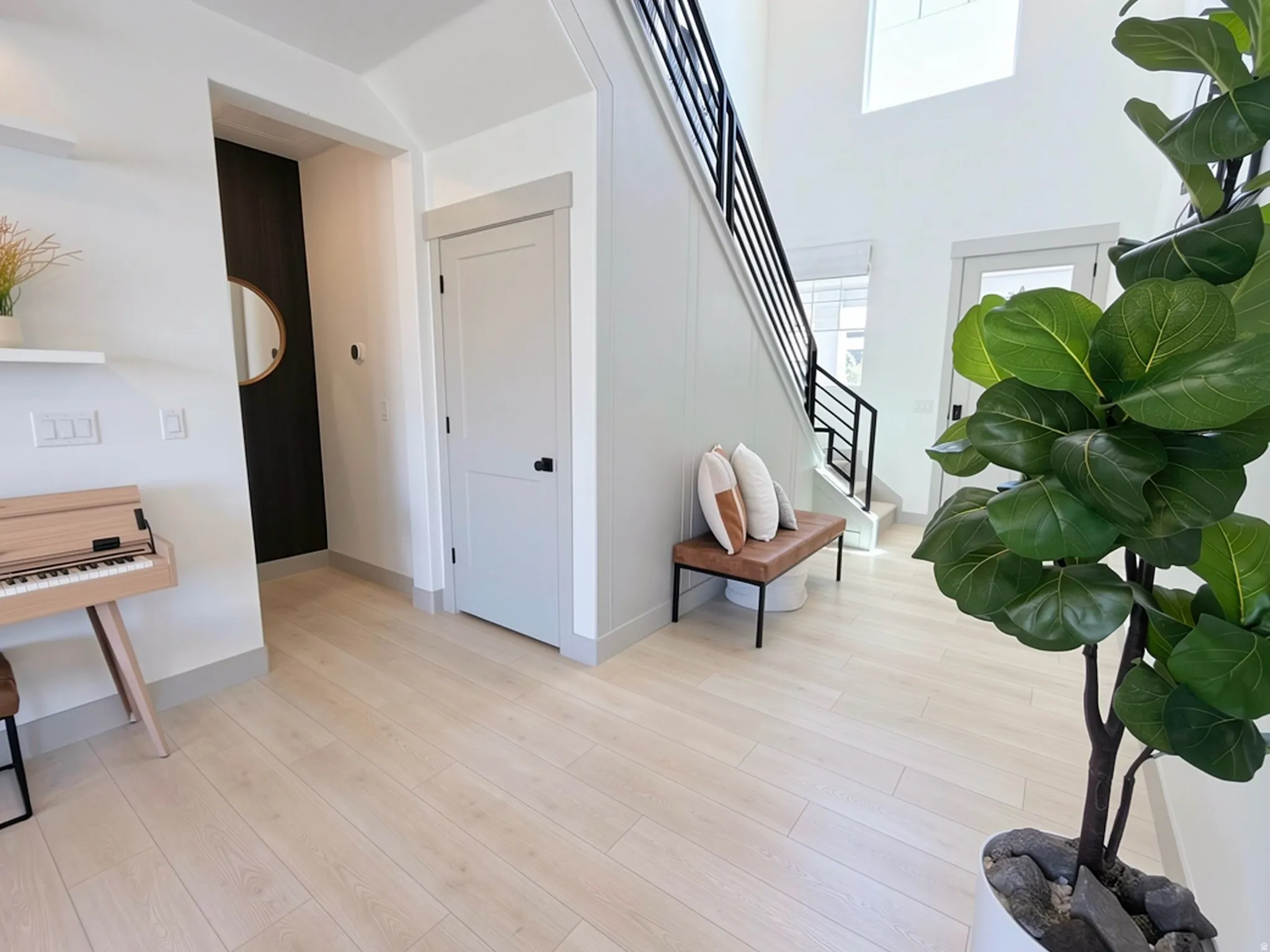 Entryway featuring light wood-finish flooring, a contemporary staircase with black metal railings, and a two-story ceiling