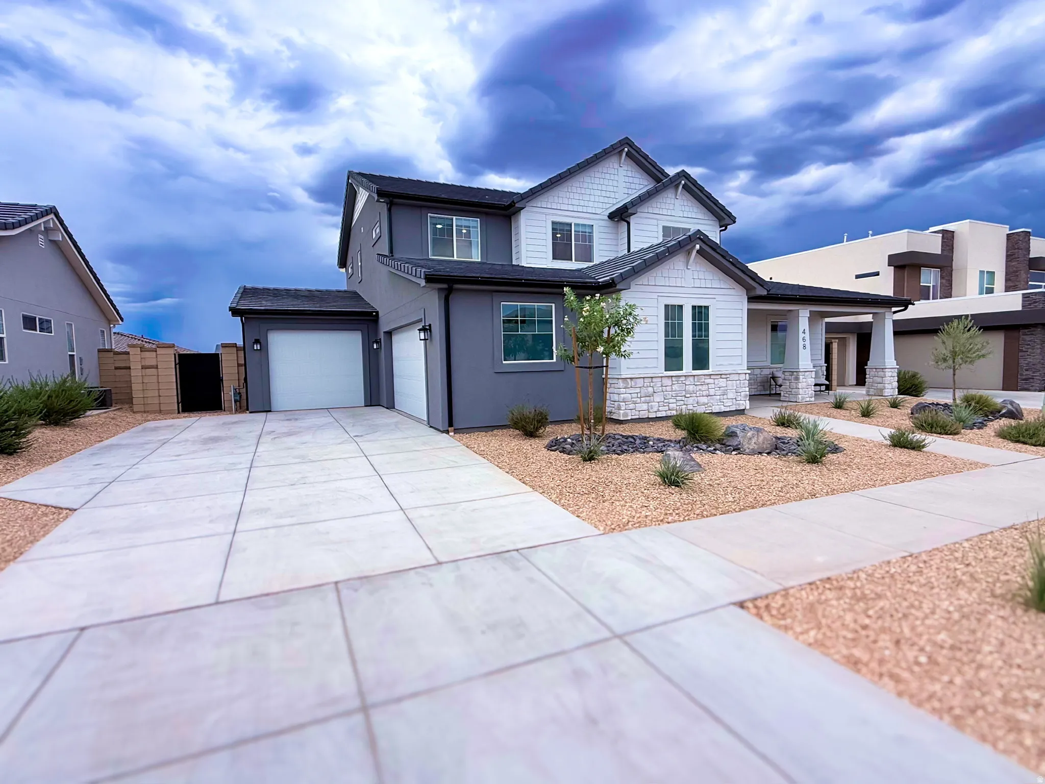 Contemporary two-story residence featuring a two-car garage, partial stone facade, and a covered front porch