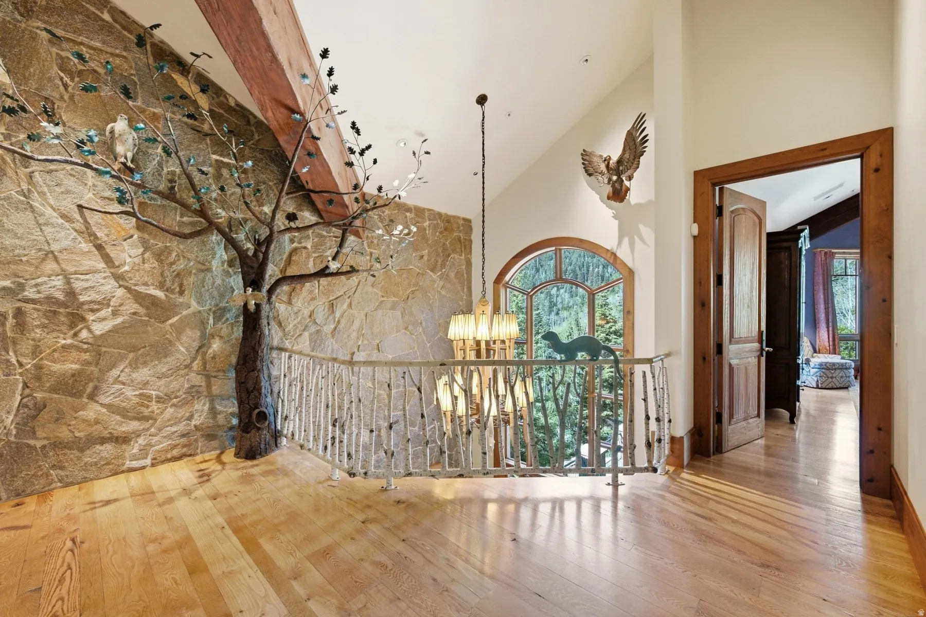 Stone accent wall featuring a decorative tree sculpture and exposed wood beam