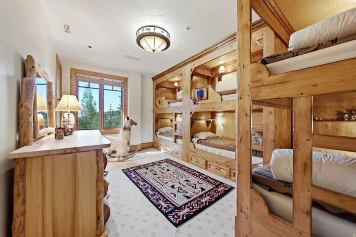 Room featuring built-in wooden bunk beds with individual lighting and storage drawers