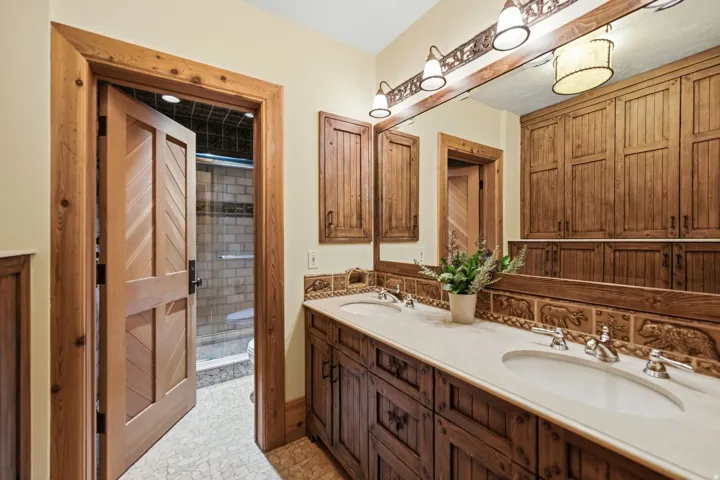 Double vanity with light-toned countertops and dual undermount sinks, set against a full-width mirror