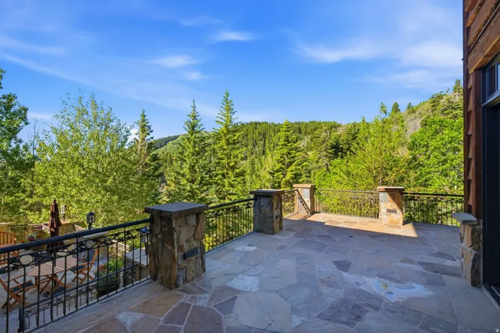 Expansive flagstone patio with wrought iron railings and stone pillars