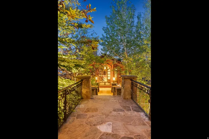 Stone paver walkway with wrought iron railings, leading to a wooden entrance