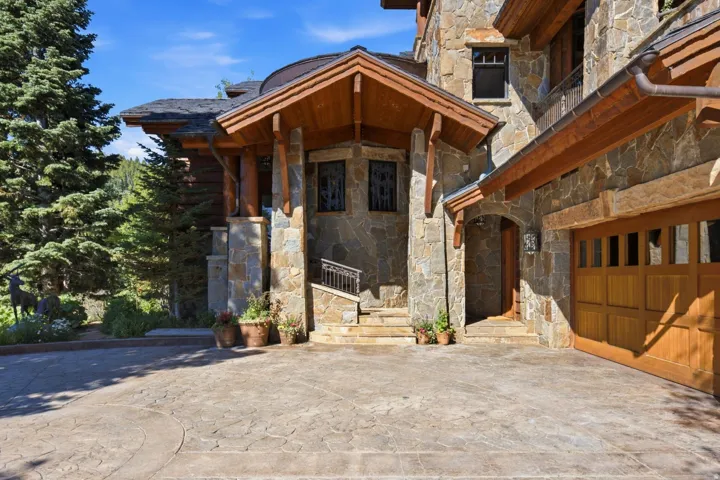 Stone facade residence with a prominent gabled entry featuring exposed wood beams and columns