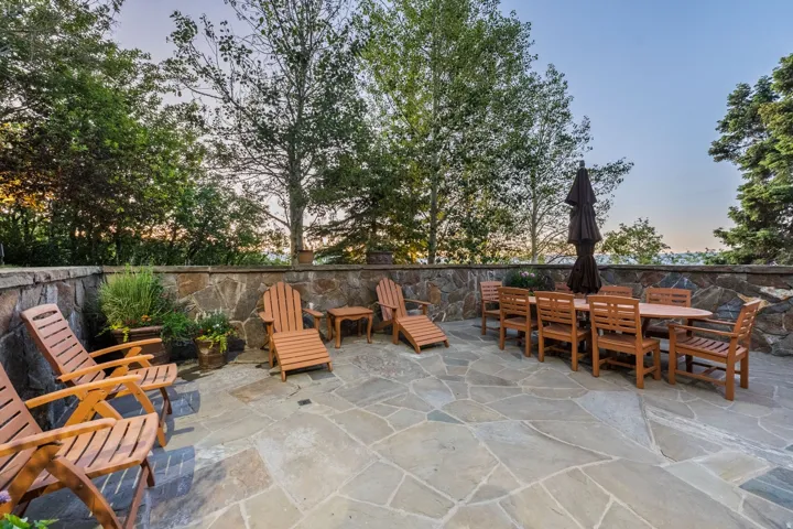 Expansive stone patio featuring natural flagstone paving and a stone retaining wall