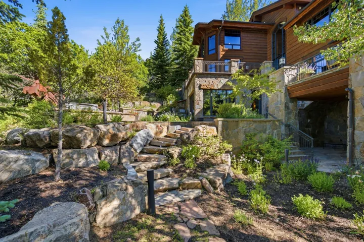 Multi-level stone retaining walls featuring natural rock steps, mature trees, and landscaping