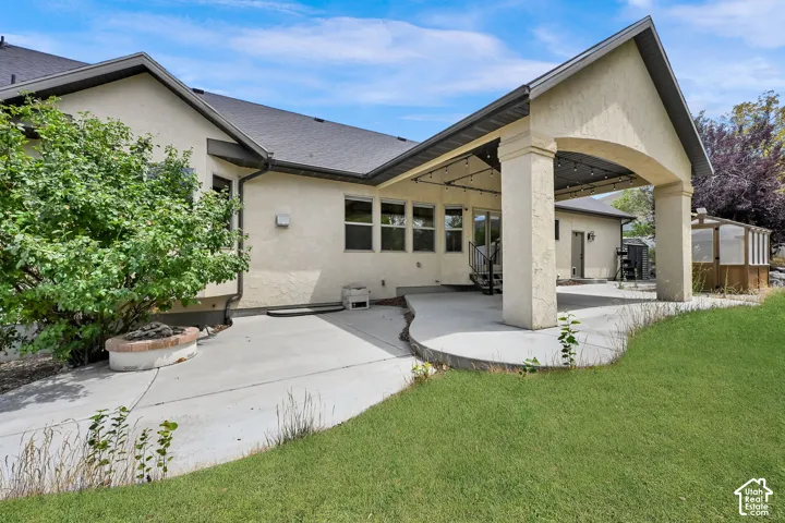 Stucco exterior featuring an expansive concrete patio and a covered outdoor living area