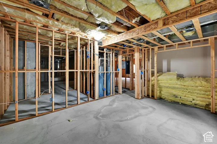 Unfinished lower level with wood framing, exposed ceiling joists, concrete flooring, and insulation