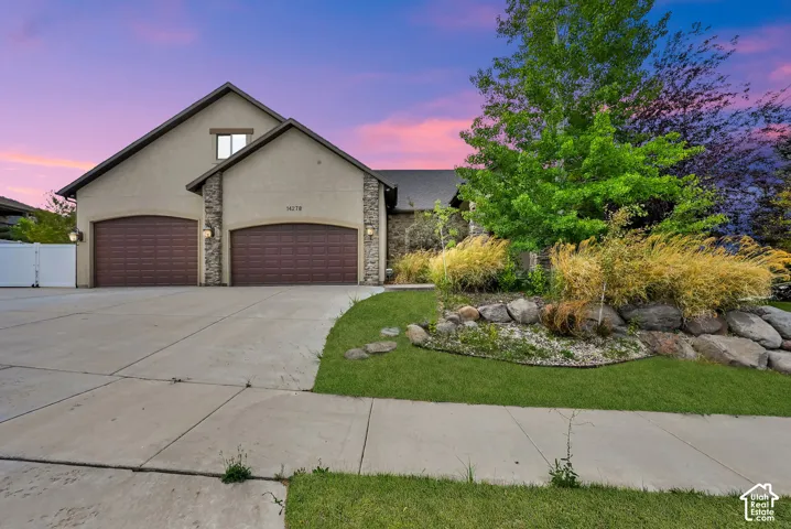 Stucco exterior with stone accents and two arched garage doors