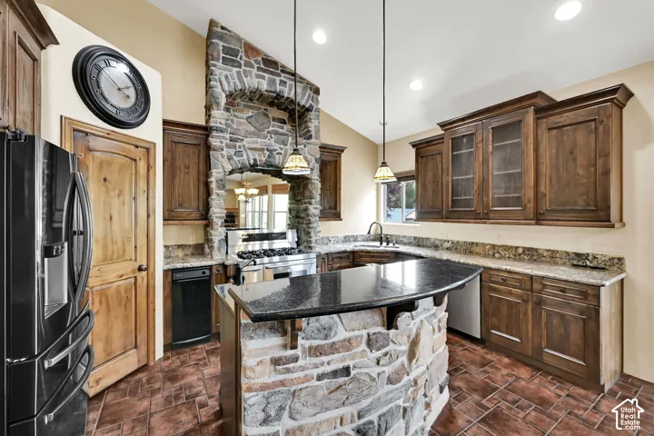 Kitchen featuring a stone archway surrounding the range, a stone-front island with a dark countertop, and perimeter cabinetry with light-colored countertops