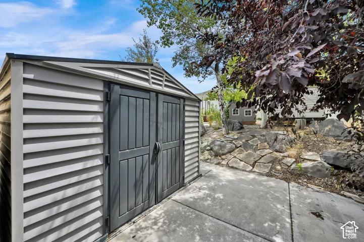 Utility shed with light-toned siding and dark-toned double doors