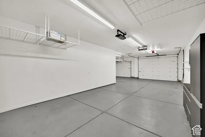 Spacious garage featuring a concrete floor, overhead storage racks, built-in cabinetry, and multiple garage doors
