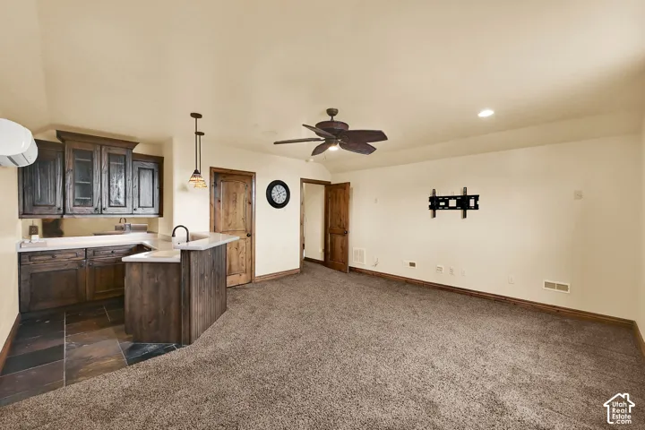 Wet bar featuring dark wood-finish cabinetry, a stone countertop, and a stainless steel sink