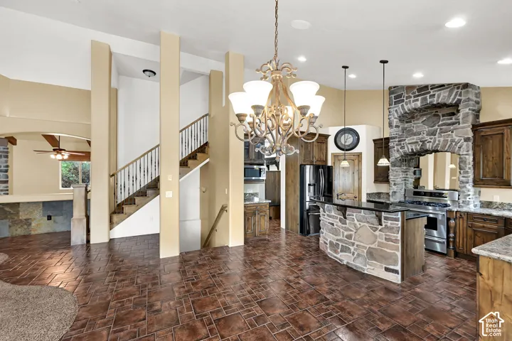 Open-concept living area with stamped concrete-look flooring, a grand staircase with white spindles, and a kitchen featuring a stone-clad island and range hood