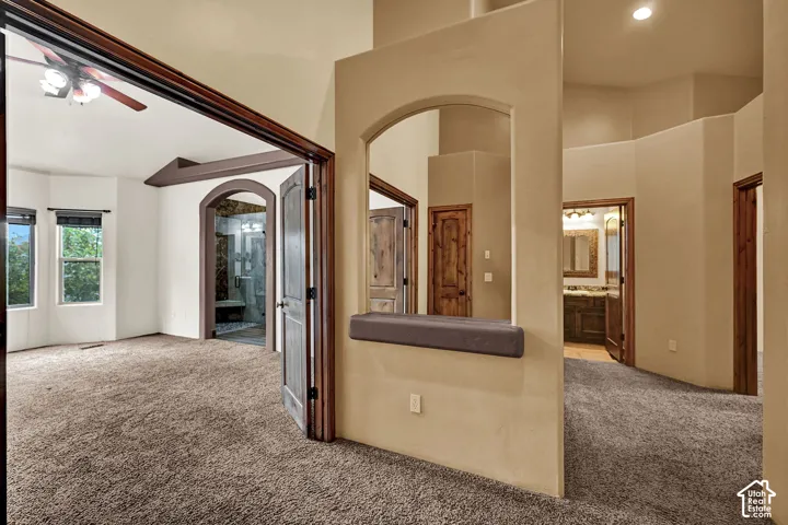 Spacious room featuring carpeting, a ceiling fan, and bay windows