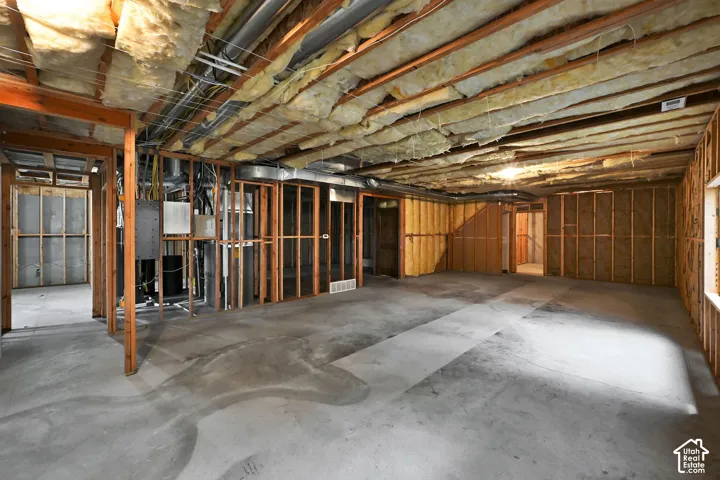 Unfinished lower level featuring exposed ceiling joists with insulation, concrete flooring, and framed interior walls