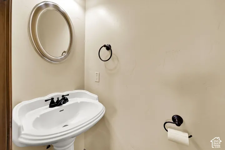 Pedestal sink with black hardware and an oval mirror